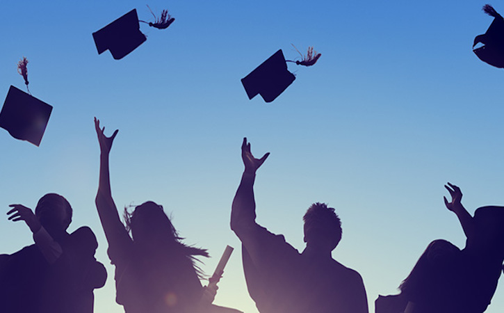 silhouette of graduates throwing their caps in the air