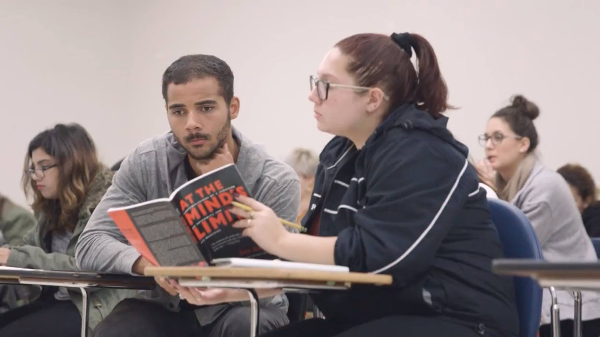 Jewish Studies students in a classroom reading a book from their desks