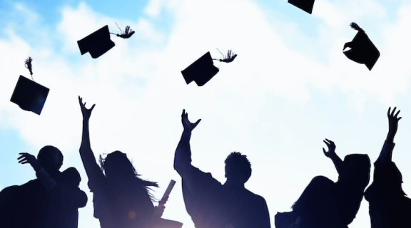 silhouette of graduates throwing their caps in the air